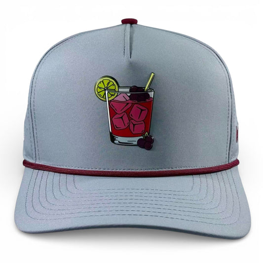The Logie Joe's Golf Transfusion Golf Hat is a light gray snapback cap with built-in magnetic ball marker holder (marker included), an embroidered cocktail patch, burgundy front trim, and adjustable fit—style and function for on or off the course.