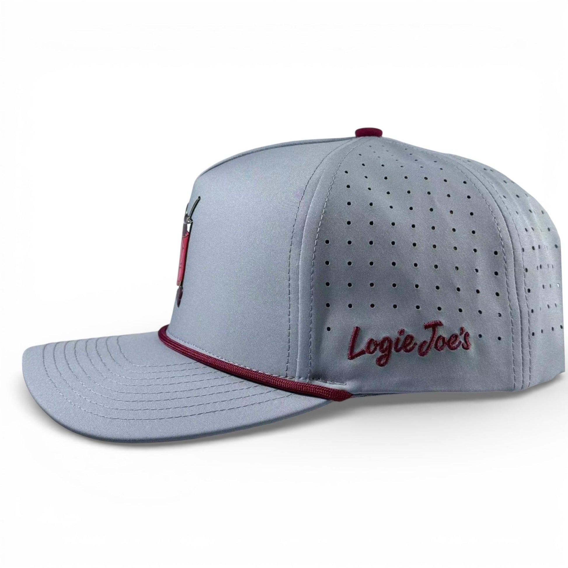 The Transfusion Golf Hat by Logie Joe's Golf is a light gray adjustable snapback featuring a small fishing lure logo, maroon accent above the visor, ventilation holes, "Logie Joes" embroidered on the side, and a magnetic ball marker holder with marker.