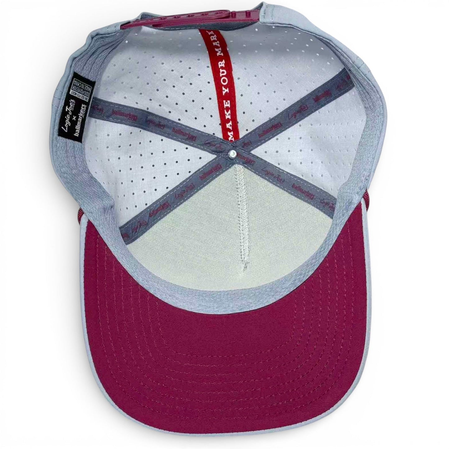 Inside view of Logie Joe's Golf Transfusion Golf Hat—an adjustable light gray snapback with white perforated lining, internal labels, red “MAKE YOUR MARK” strip, and a built-in magnetic ball marker holder plus marker included.