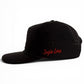 A black snapback cap from Logie Joe’s Golf, the Jogie Loe’s Flamingo Golf Hat features small ventilation holes, an adjustable fit, and a built-in magnetic ball marker holder with marker included. Reminiscent of a classic golf hat, it is shown on a white background with distinctive red embroidered detailing.