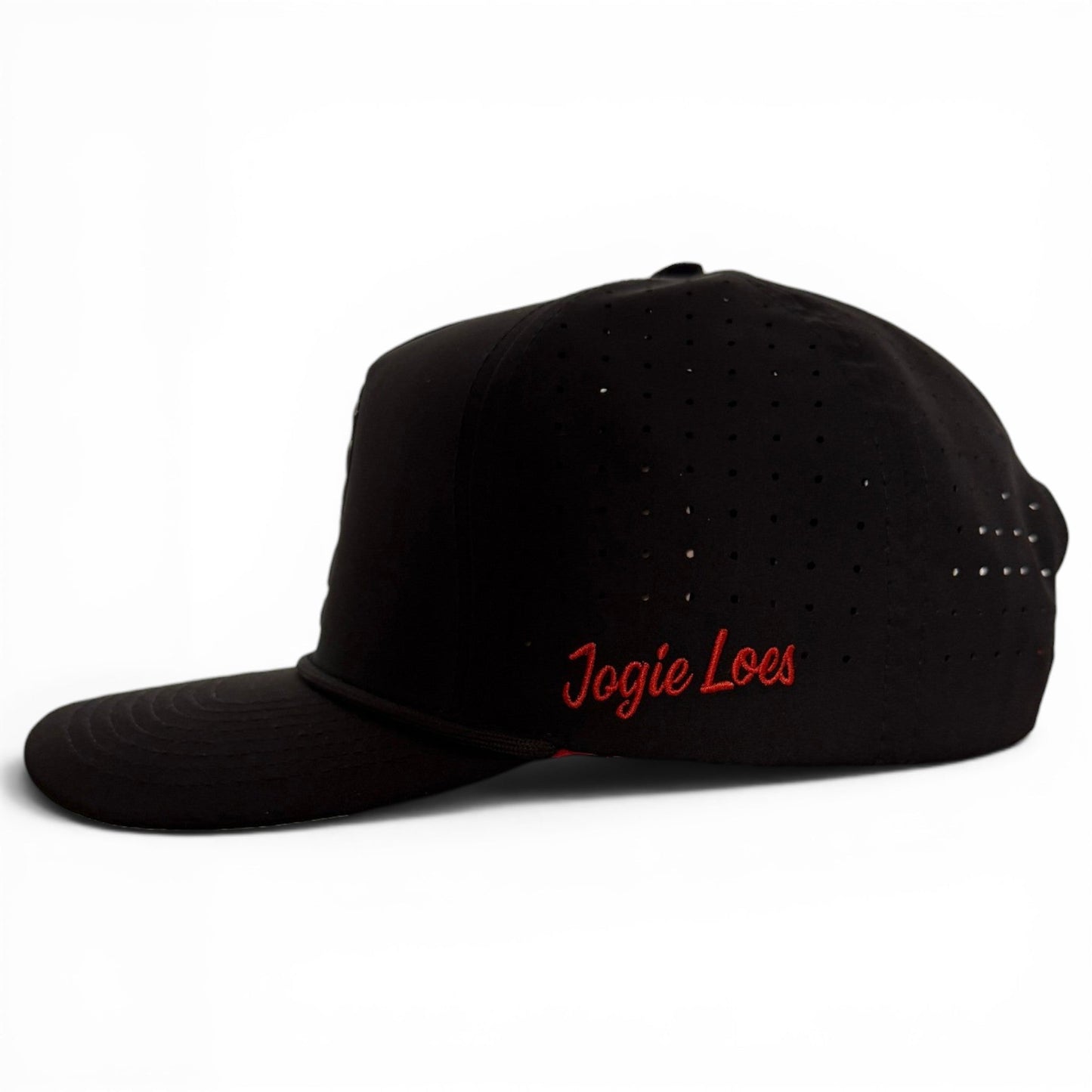 A black snapback cap from Logie Joe’s Golf, the Jogie Loe’s Flamingo Golf Hat features small ventilation holes, an adjustable fit, and a built-in magnetic ball marker holder with marker included. Reminiscent of a classic golf hat, it is shown on a white background with distinctive red embroidered detailing.