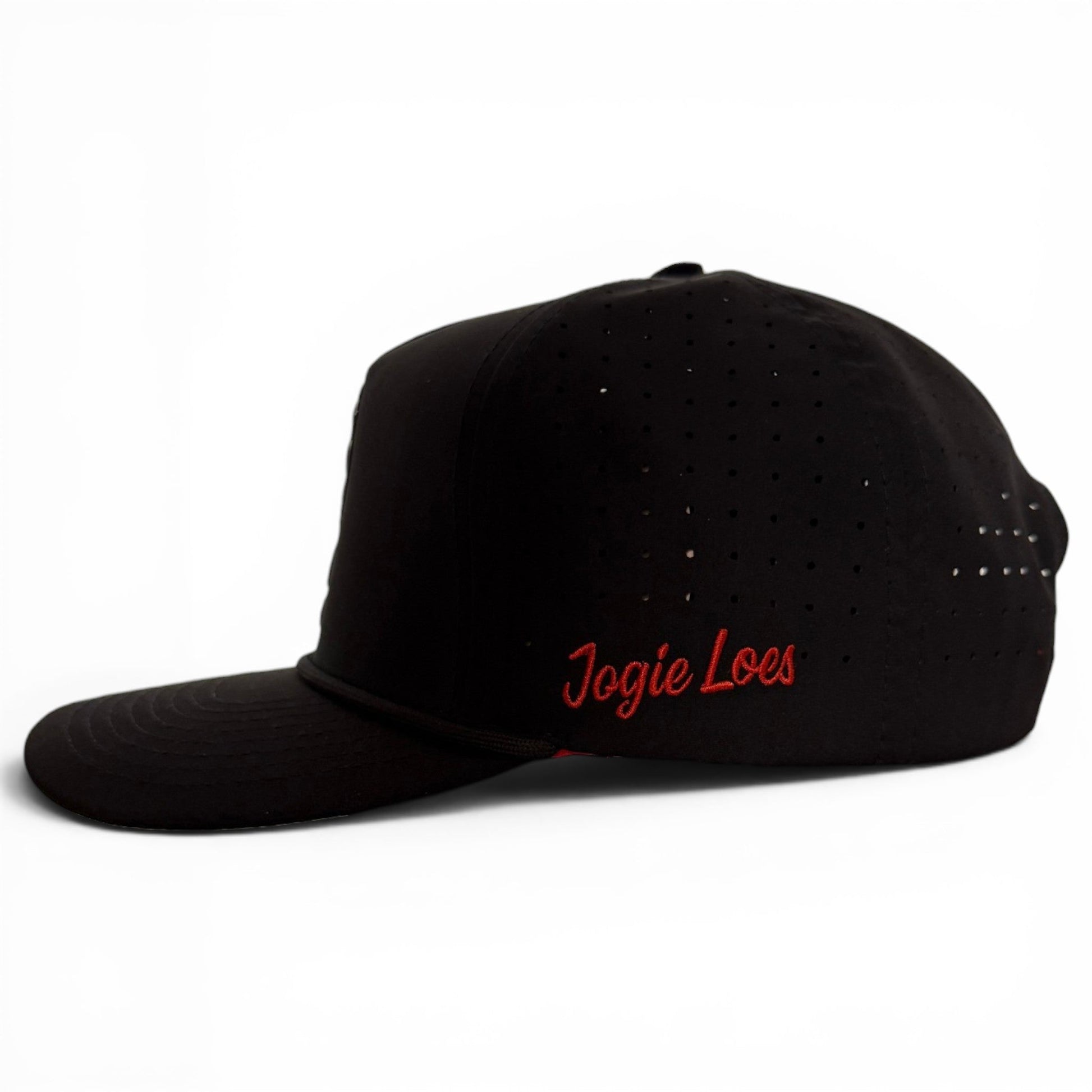 A black snapback cap from Logie Joe’s Golf, the Jogie Loe’s Flamingo Golf Hat features small ventilation holes, an adjustable fit, and a built-in magnetic ball marker holder with marker included. Reminiscent of a classic golf hat, it is shown on a white background with distinctive red embroidered detailing.