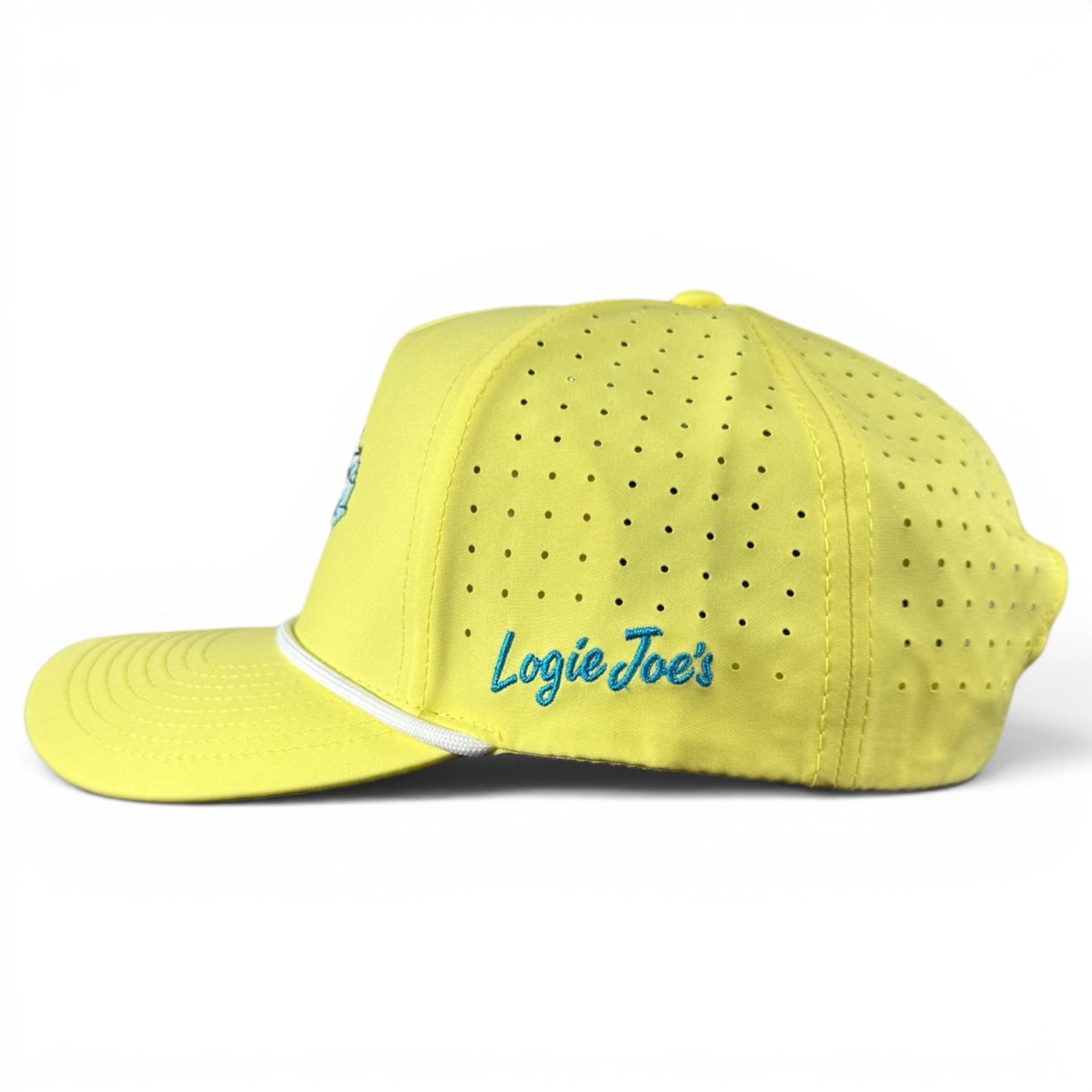 A yellow Motor Boatin’ Golf Hat by Logie Joe’s Golf is displayed against a white background. This snapback cap is designed for golf and features ventilation holes, an adjustable fit, and a white trim above the brim. “Logie Joe’s” is embroidered in blue on the side, and the hat includes a built-in magnetic ball marker holder with marker included.