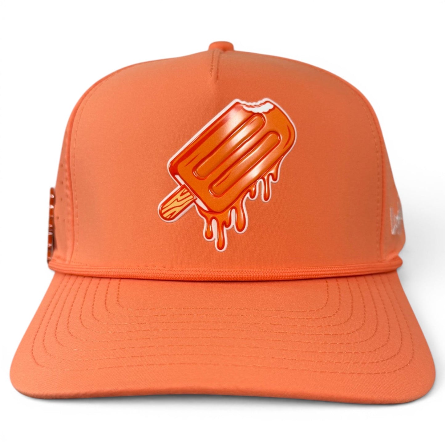 The Logie Joe’s Golf Orange Dream Golf Hat is an adjustable snapback cap featuring a playful graphic of a melting orange popsicle with a bite taken out of it on the front panel. This stylish orange baseball cap also includes a built-in magnetic ball marker holder and comes with a marker.