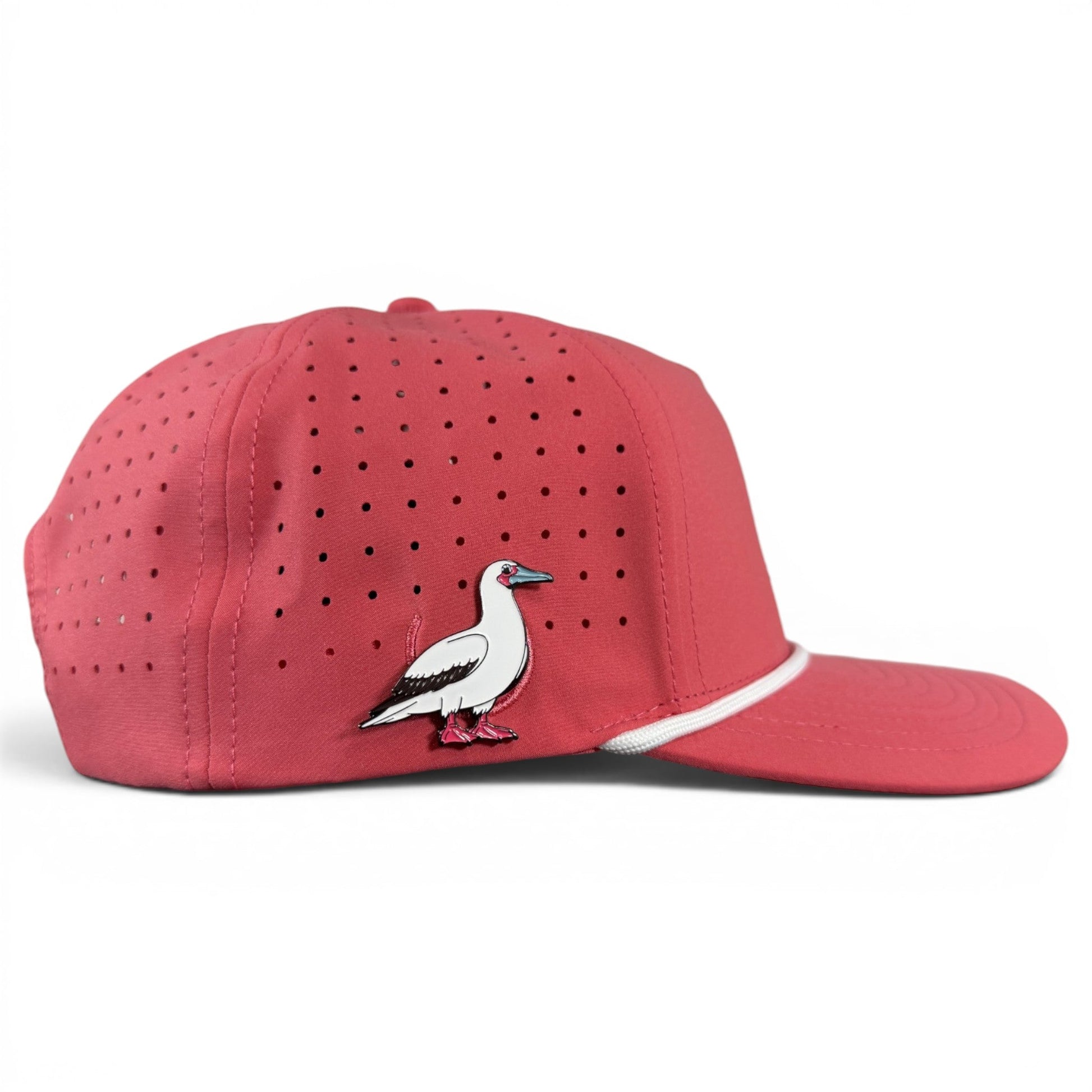 The Redfoot Birdie Golf Hat by Logie Joe’s Golf is a snapback cap in vibrant red, featuring small ventilation holes and an attached pin of a white Red Footed Booby with red feet and beak. This adjustable hat includes a built-in magnetic ball marker holder and comes with a marker, offering both style and functionality for golf enthusiasts.