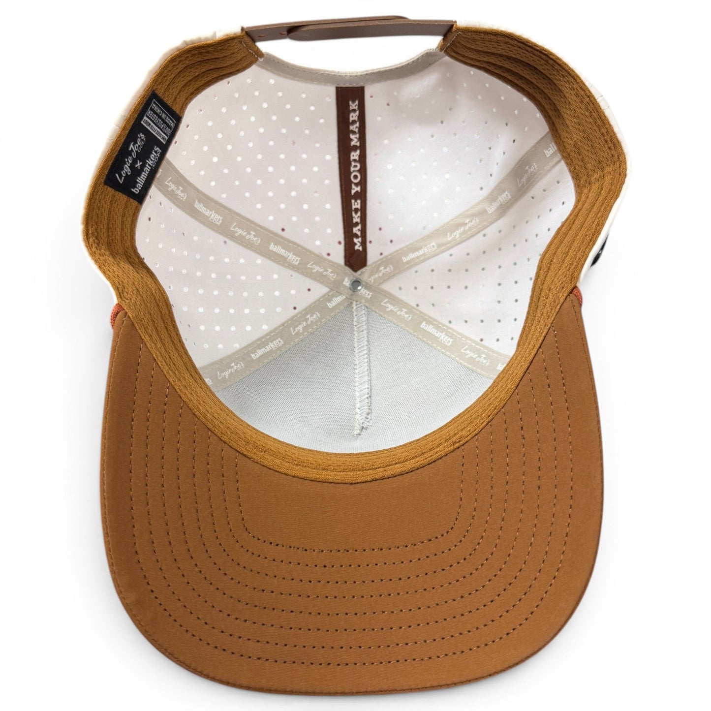 Top view of the inside of a brown Logie Joe’s Golf Old Fashioned Golf Hat Snapback Cap, featuring a structured brim, white dotted lining, and beige crisscrossing sweatbands. The inner seams and bands display visible text, and for added convenience, an integrated magnetic ball marker holder with a marker included is subtly built into the design.