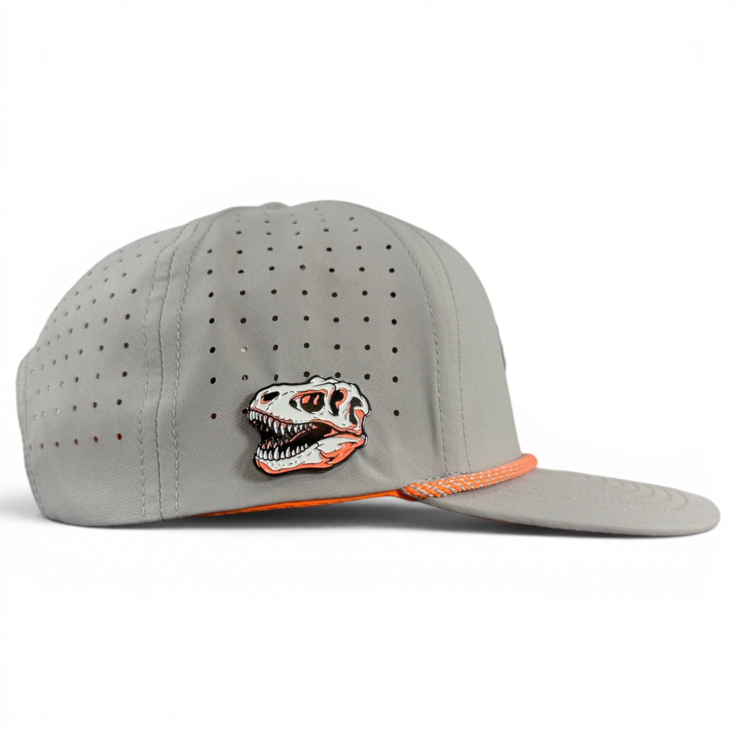Experience comfort and style with the Logie Joe’s Golf Fossil Fairway Golf Hat—a gray snapback cap featuring ventilation holes, an orange trim, and a distinctive dinosaur skull pin on the side. Designed for golf enthusiasts, it comes with an adjustable fit and includes a built-in magnetic ball marker holder plus marker for added convenience on the course.