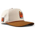 Introducing the Old Fashioned Golf Hat by Logie Joe’s Golf, a beige and brown snapback cap inspired by classic styles. This adjustable hat features a cartoon cocktail glass patch with an orange slice and cherry on the front, along with a smaller matching patch on the side. Designed for golfers, it offers ventilation holes for comfort and includes a built-in magnetic ball marker holder with marker included—perfect for your next round.