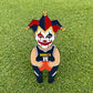 Pin Creatures' "Joker" is a cartoon pin of a Denver Nuggets player in jersey 15 with a jester mask, standing on green grass. It features a built-in golf ball marker and a magnetic hat clip, adding extra fun to your golf game.