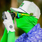 A golfer in a green suit and sunglasses, wearing a white cap and golf glove, uses a rangefinder while sporting the Pins and Aces HEYDUDE Logo Ball Marker outdoors.