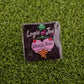 Add a playful touch to your game with Ballmarkers by Logie Joes Lick Em golf ball marker, featuring an ice cream cone with cherry-topped scoops and the phrase “Lick Em.” Displayed on artificial grass for a fun twist.