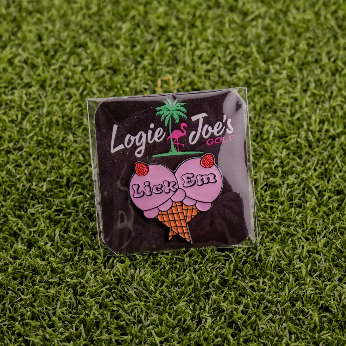Add a playful touch to your game with Ballmarkers by Logie Joes Lick Em golf ball marker, featuring an ice cream cone with cherry-topped scoops and the phrase “Lick Em.” Displayed on artificial grass for a fun twist.