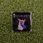 The Hawk Tuah Llama pin by Logie Joe's Golf features a cartoon llama with a blue fish, displayed on a black LOGIE JOE'S card atop green turf—perfect for fans of unique golf accessories or playful ball markers.