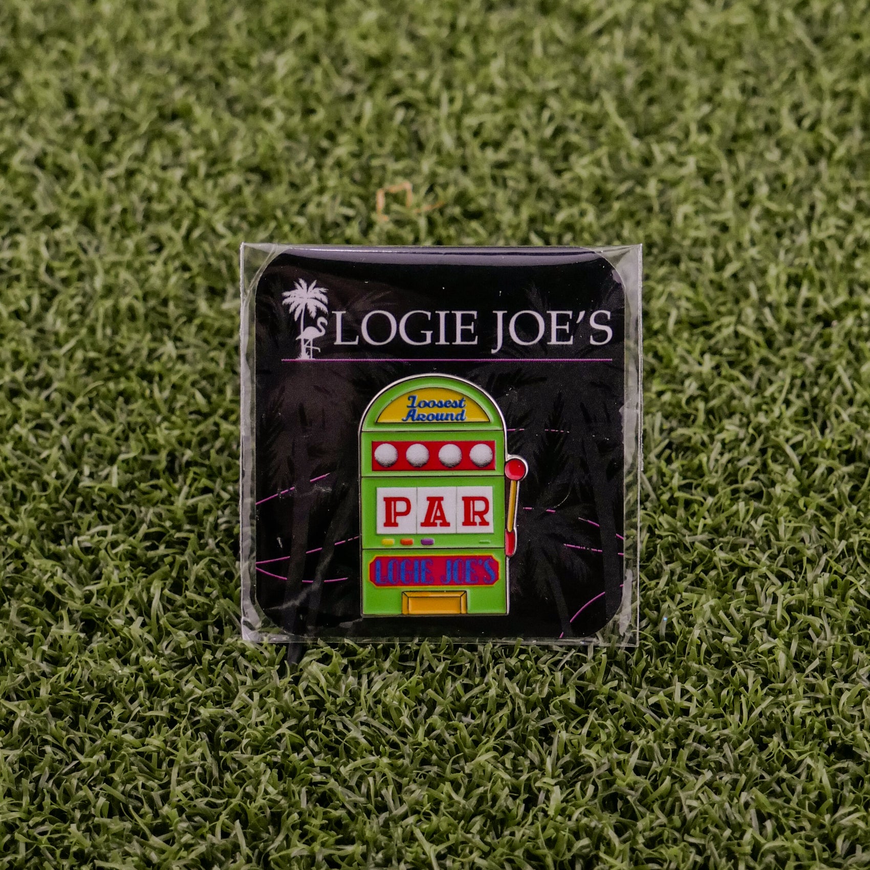 A square pin from Ballmarkers by Logie Joes, featuring a colorful slot machine and “LOGIE JOE’S” on black—perfect as a unique golf ball marker or a fun gift for fans of quirky golf accessories.