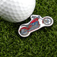 A Logie Joe's Golf white ball rests on green grass beside the Motorcycle pin-shaped red ball marker, adding flair to your premium golf accessories collection.