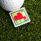 The December Mushroom Stamp Ball Marker by Ballmarkers.com features red mushrooms on a yellow and green background, with "Forever 69¢" and "12.2015" text—ideal as a unique golf ball marker for your game.