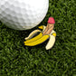 A golf ball sits on green grass next to Logie Joe's Golf Nannerdick, a novelty banana-shaped premium ball marker humorously resembling a penis—perfect for golfers who enjoy playful, artistic accessories.