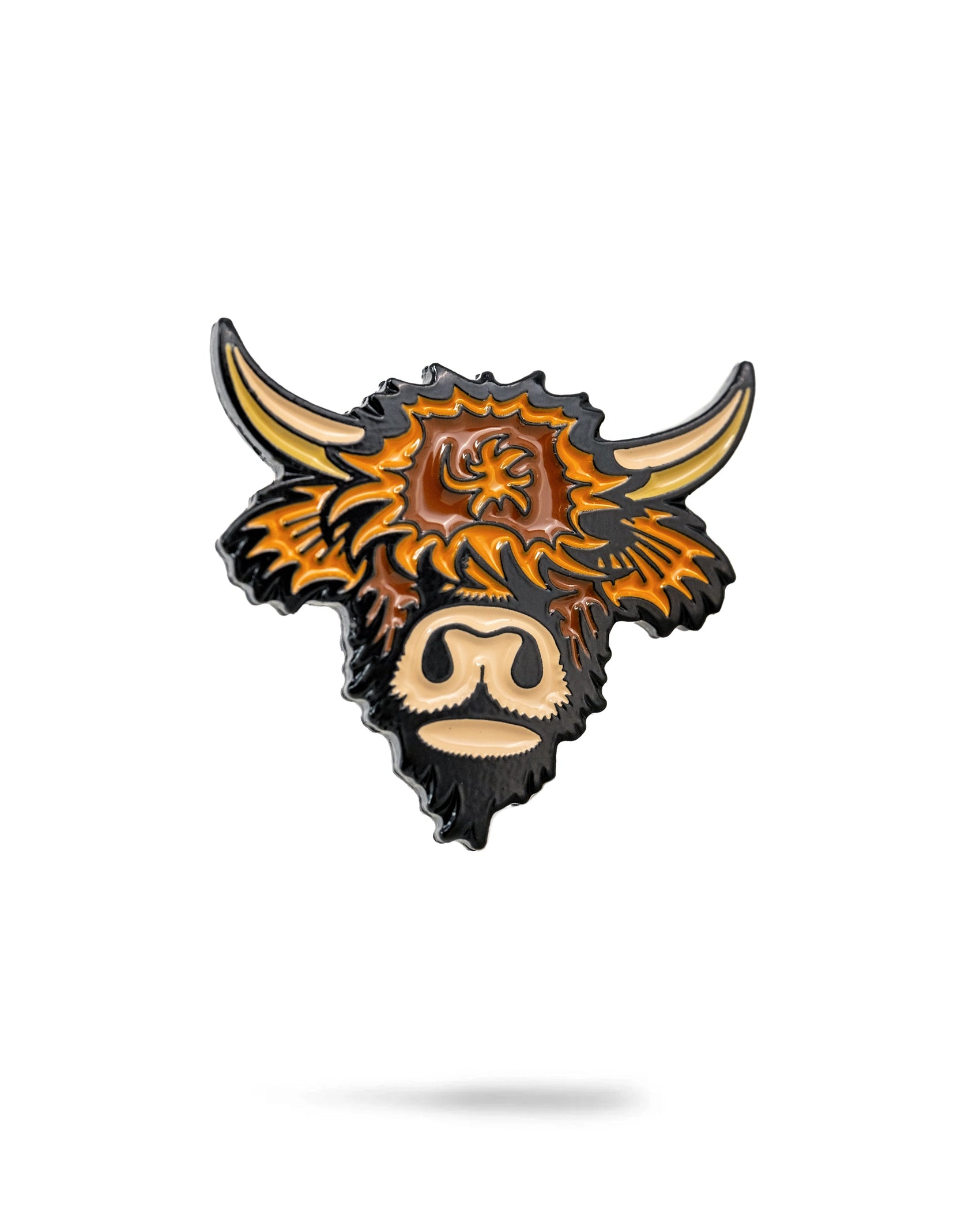 The Highland Cow Ball Marker by Pins and Aces is a cast metal and enamel marker featuring a stylized highland cow head with shaggy orange and brown fur, large curved horns, and a beige snout on a white background.