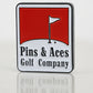 The Pins and Aces Pins Reds Ball Marker is a rectangular enamel badge featuring a red and white design with a golf flag on green, plus "Pins & Aces Golf Company" text below the image.