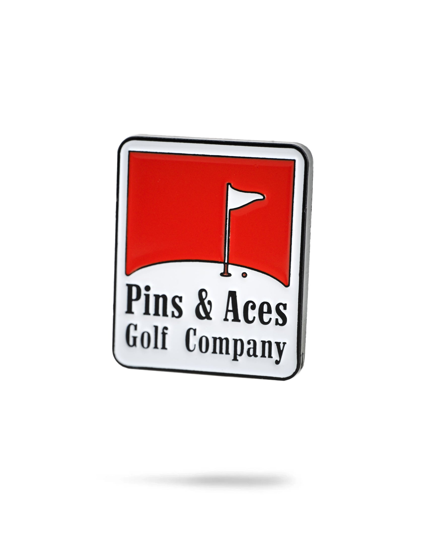 The Pins and Aces Reds Ball Marker is a rectangular enamel pin with a red flag on white above "Pins & Aces Golf Company" in black, featuring durable enamel paint and a classic golf-themed design.