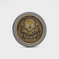 The Doubloon Omen Classic Antique is a round gold and black coin featuring an ornate skull and crossbones with sparkling gemstone eyes and “MARKS THE SPOT” engraved below.