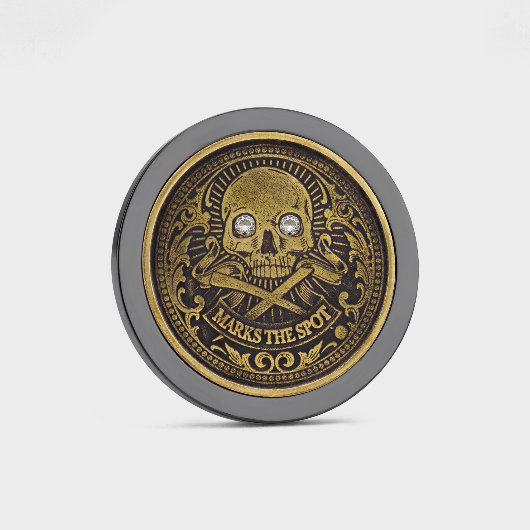 The Doubloon Omen Classic Antique is a round gold and black coin featuring an ornate skull and crossbones with sparkling gemstone eyes and “MARKS THE SPOT” engraved below.