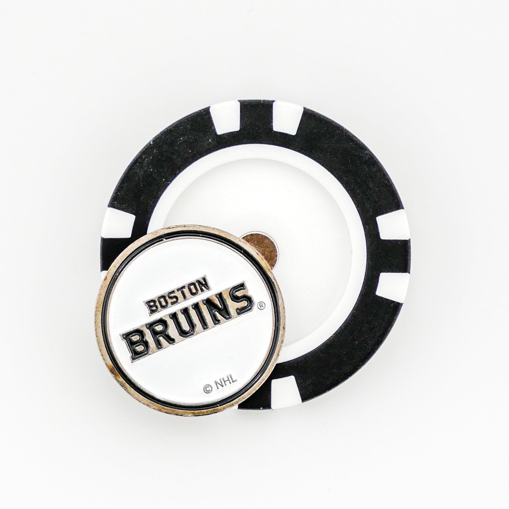 A Ballmarkers by Logie Joes Boston Bruins NHL pin sits atop a black and white poker chip, both displayed on a plain white background.