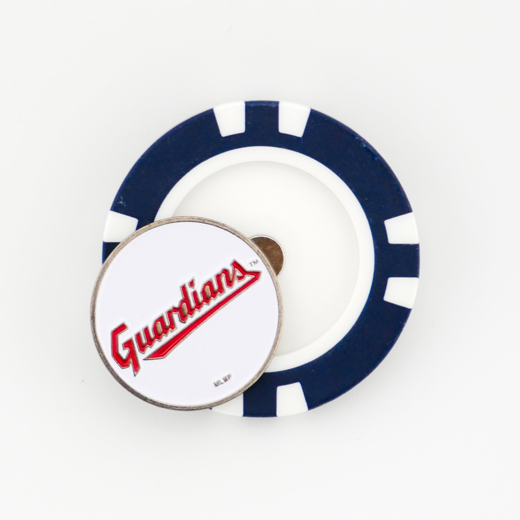 A round poker chip-style marker by Ballmarkers.com, featuring blue and white segments, lies on a white surface. On top is a circular metal Cleveland Guardians marker with “Guardians” in red script.