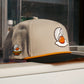 The Logie Joe's Golf Breakfast Ball Snapback Hat + Matching Ball Marker in beige and black features an embroidered egg-shaped golf ball with orange yolk, a “Breakfast Ball” side patch, and a built-in magnet for your marker.