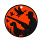 The Duck Hunter Putting Disk by Logie Joe's Golf features a round, orange and black design with a hunter, dog, and flying ducks—ideal as a unique putting aid or stylish accessory for golf enthusiasts.