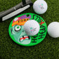 The Helmet Head Hills Putting Disk by Logie Joe's Golf features a cartoon zombie face and "FORE!"—a colorful marker perfect for stroke training, shown on green turf beside a putter and three Logie Joe's golf balls.