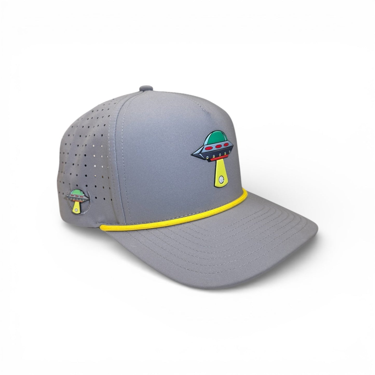 The Logie Joe's Golf UFO Golf Hat in Alien Gray features a colorful UFO and beam graphic, yellow trim, ventilation holes, adjustable snapback, and includes a magnetic ball marker holder with marker. Displayed on a white background.