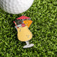 The Piña Colada Ball Marker by Ballmarkers.com, a vibrant enamel pin featuring a straw, umbrella, and fruit garnish, is shown on green grass next to a white golf ball.