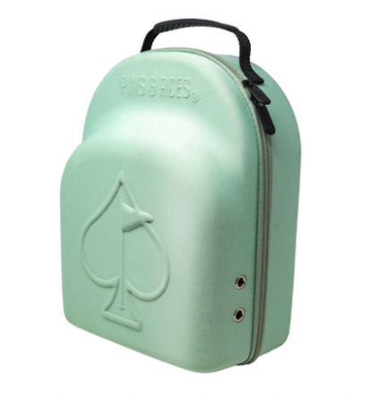 The Pins and Aces Hat Caddie is a light green hard-shell golf hat case with a spade symbol on the front, two small vents, a black handle, and a zipper around the edge.