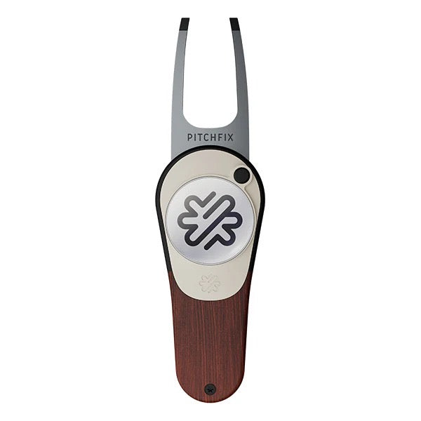 The PitchFix Woodie Divot Tool features a wood-effect handle, silver prongs, and a circular emblem with a geometric logo at the center. The elegant tool displays the PitchFix brand above the logo.