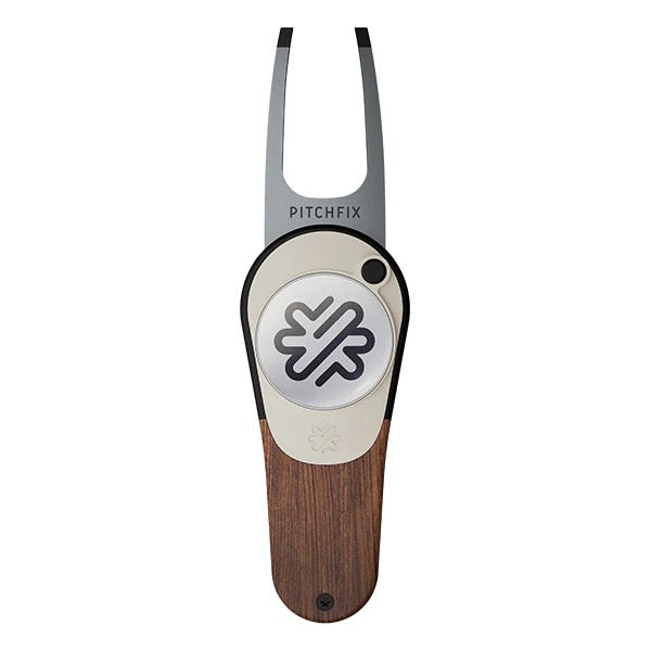 The PitchFix Woodie Divot Tool is a metal and wood-effect divot repair tool with a circular emblem and geometric logo on the handle.