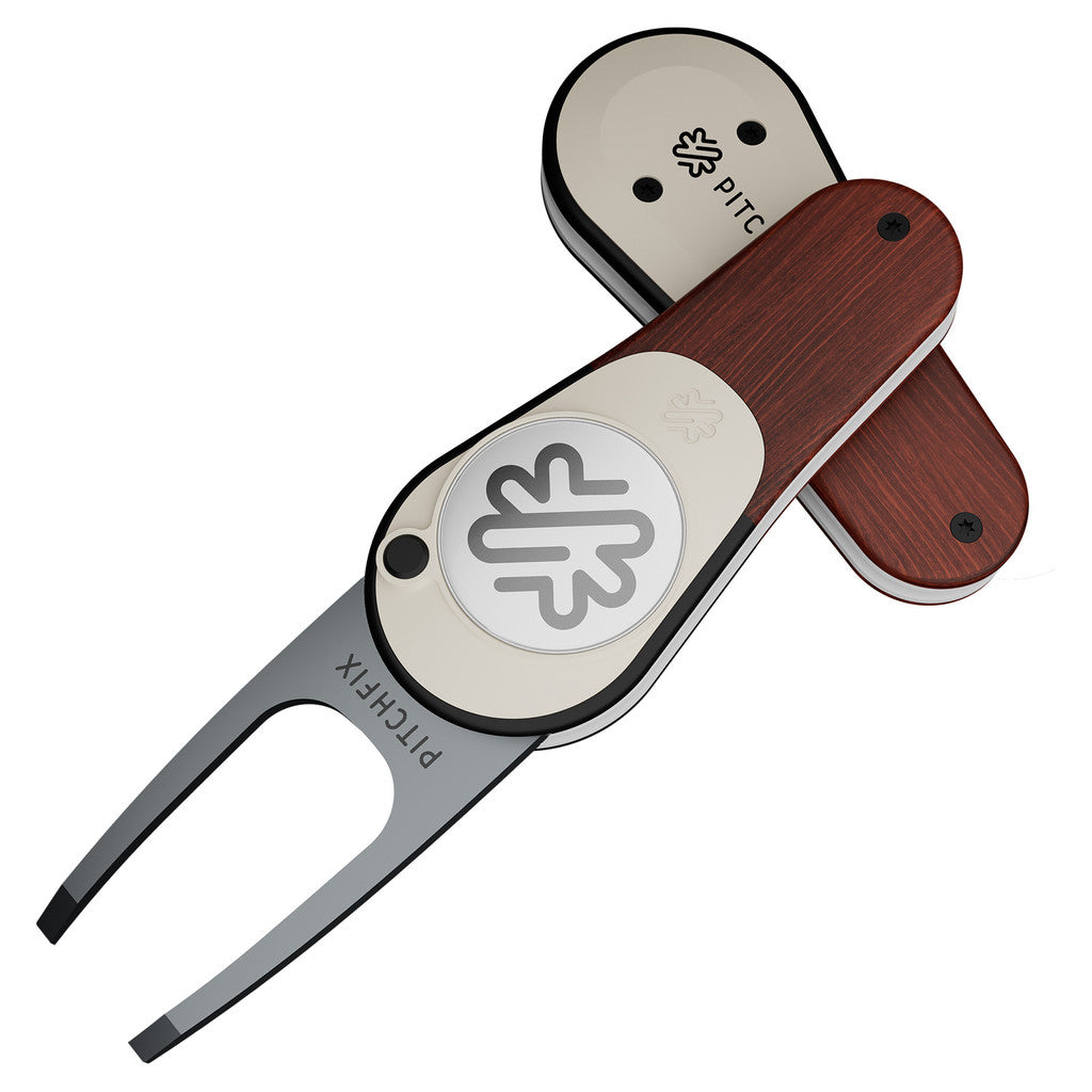 The PitchFix Woodie Divot Tool features a soft touch finish, wood-effect design, circular emblem, and engraved PITCHFIX branding. Shown in both open and closed positions.