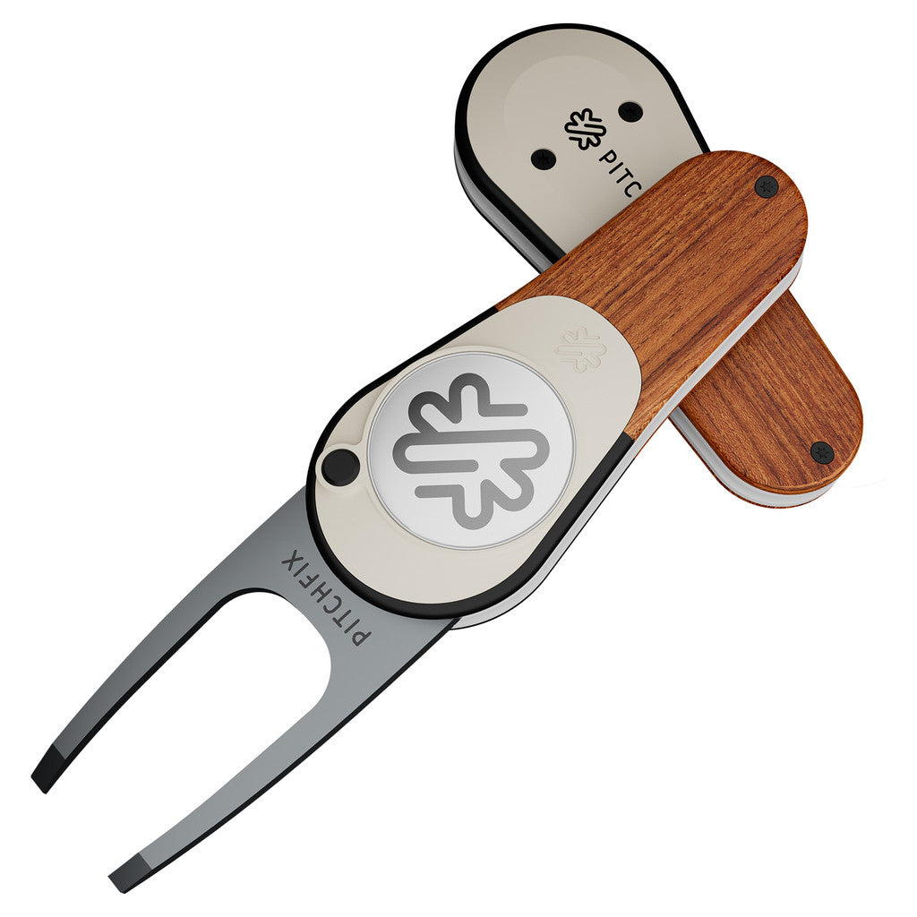 The PitchFix Woodie Divot Tool by PitchFix features a metal fork, wood-effect styling, and a silver circular emblem with a leaf logo. Shown open and closed, it's an elegant accessory for any golfer.