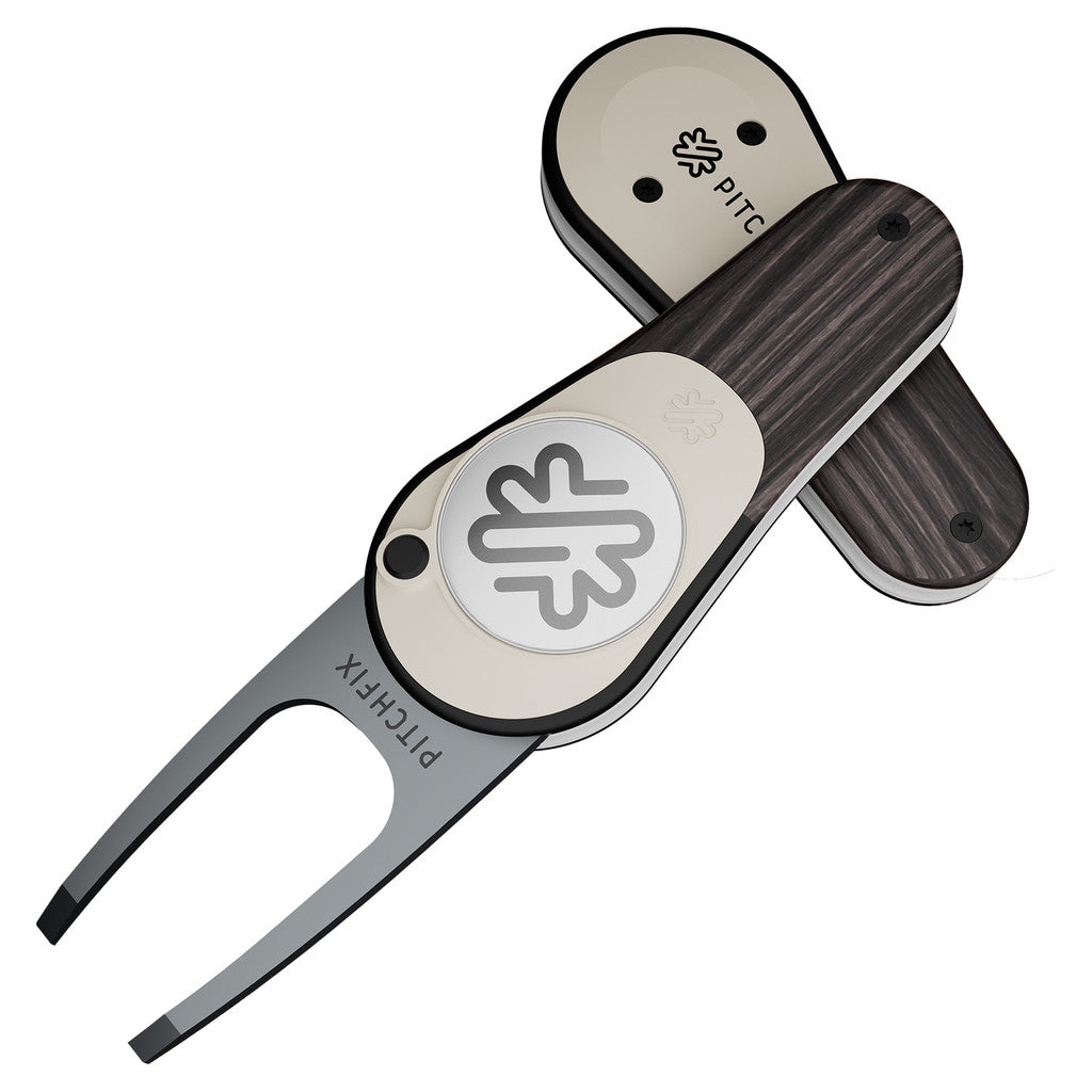 The PitchFix Woodie Divot Tool combines sleek metal and wood-effect styling with a detachable ball marker, minimalist leaf logo, and "PITCHFIX" engraved on the prongs. Its soft touch finish offers a refined, premium feel.
