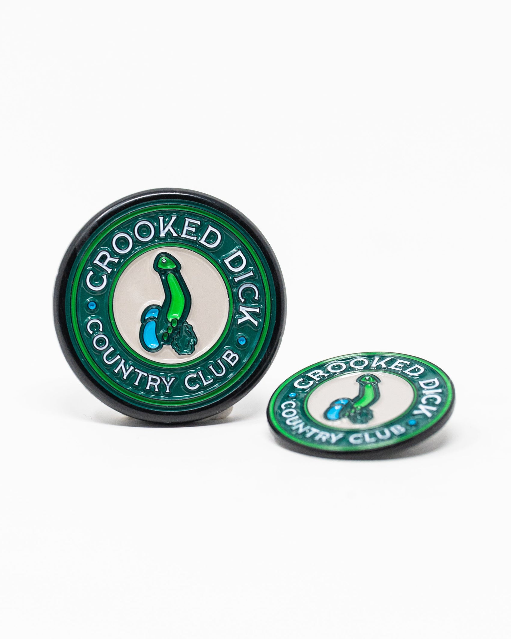 The Pins and Aces Pop Out Medallion Ball Marker - Crooked Dick is a hat clip and ball marker set with a green border, featuring "CROOKED DICK COUNTRY CLUB" and an illustration of a bent green golf tee with golf balls.