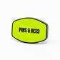 A yellow-green HEYDUDE - Logo Ball Marker by Pins and Aces, with black edges and bold black "PINS & ACES" text on the front, set against a plain white background.