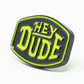 The Pins and Aces HEYDUDE - Logo Ball Marker is a black cast metal marker with rounded edges, featuring bold raised yellow-green "HEY DUDE" text outlined in the same color. Shown on a white background.