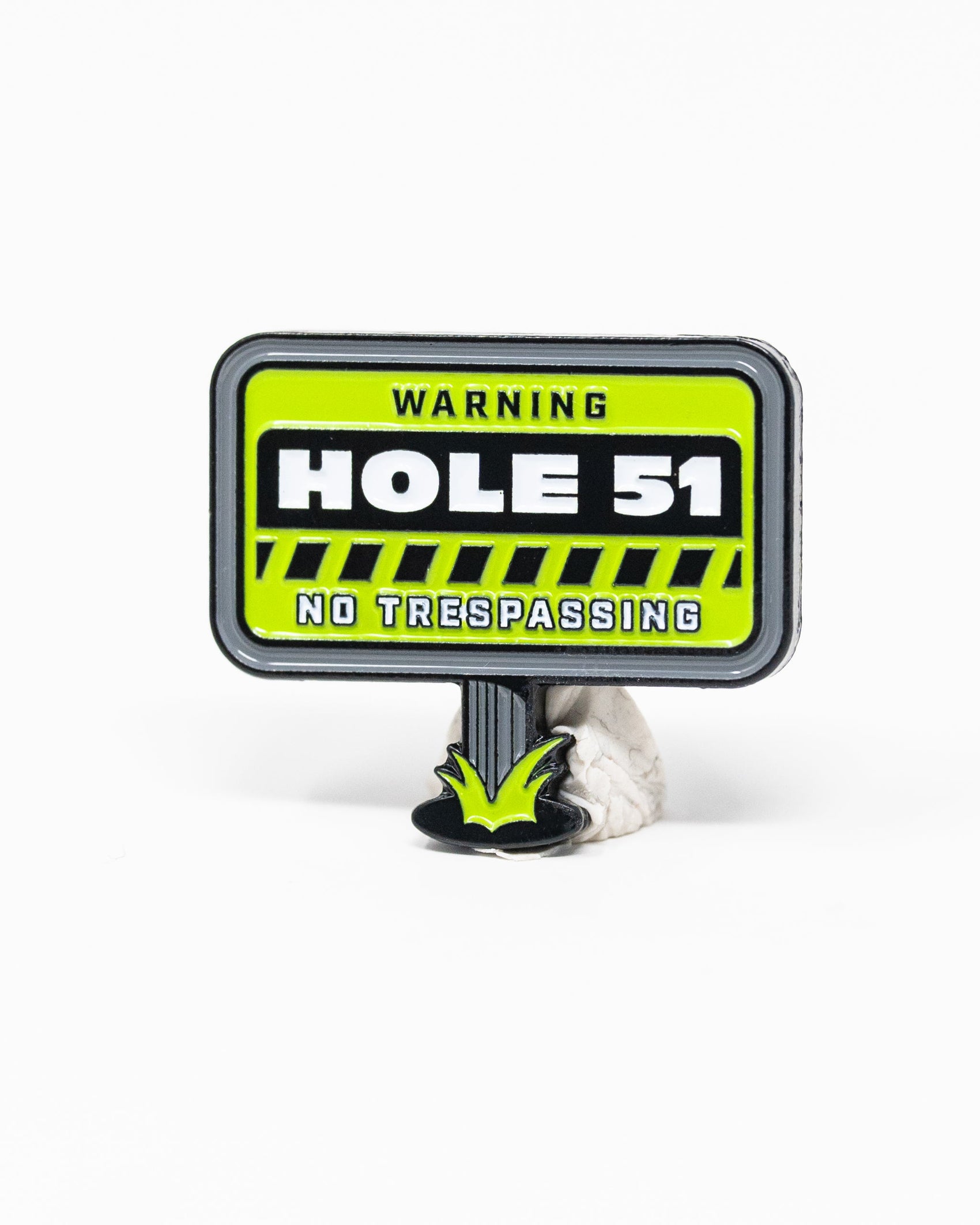 The HEYDUDE - Hole 51 Ball Marker by Pins and Aces is a green and black, warning sign-shaped cast metal ball marker featuring "WARNING HOLE 51 NO TRESPASSING" and a patch of grass at the base—perfect for ball marker collections.