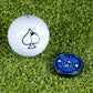 A Pop Out Medallion Ball Marker - Navy by Pins and Aces and a white golf ball with a black spade symbol rest on green artificial turf.