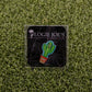 The Don’t be a Prick cactus pin by Ballmarkers by Logie Joe’s, featuring an angry face and red pot on branded black backing over faux grass, is ideal for anyone seeking a funny golf accessory or unique golf ball marker.