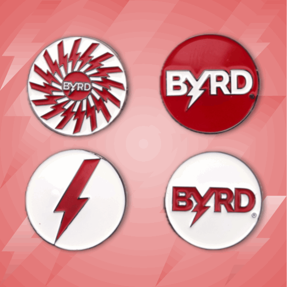 BYRD BALL MARKERS - All logos by The Byrd, LLC: Four round magnetic golf accessories on a pink geometric background, each with BYRD in red and a lightning bolt, plus unique red and white designs—perfect for your game.