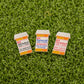 Logie Joe's Golf RX Putterall features three novelty pins shaped like prescription pill bottles—Hittadbol, Putterall, and Fuckitlol—displayed on green turf, perfect for adding playful flair to your golf bag with any divot tool or ball marker.