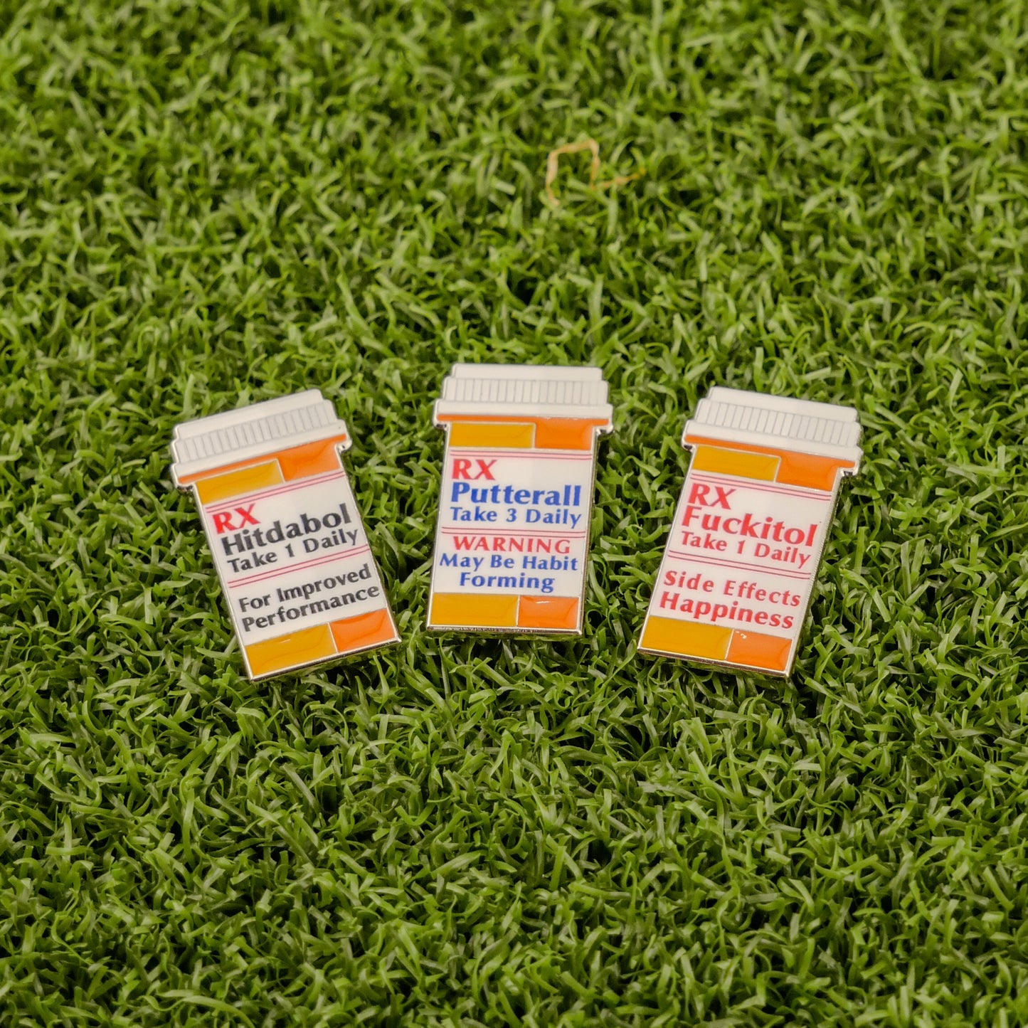 Logie Joe's Golf RX Putterall features three novelty pins shaped like prescription pill bottles—Hittadbol, Putterall, and Fuckitlol—displayed on green turf, perfect for adding playful flair to your golf bag with any divot tool or ball marker.