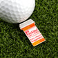 The Logie Joe's Golf "RX Fuckitol" novelty pin, shaped like a pill bottle and labeled “Take 1 Daily. Side Effects: Happiness,” adds a quirky touch to your golf accessories—shown here beside a golf ball on artificial grass.