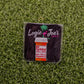 A square sticker on grass displays Ballmarkers by Logie Joe’s RX Fuckitol above a cartoon pill bottle labeled Take 1 Daily. Side effects: happiness, palm tree & flamingo—great for fans of funny golf accessories or unique golf ball markers.